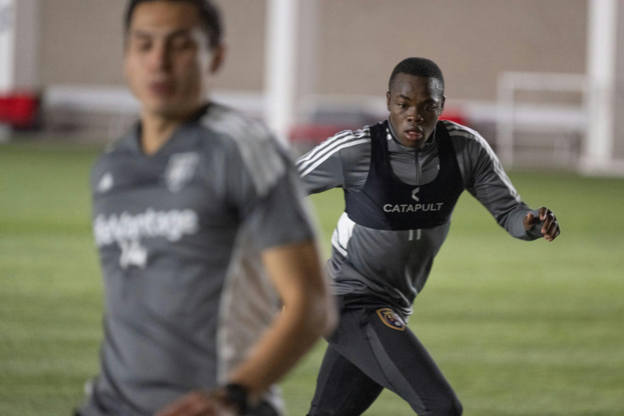 Real Salt Lake player Carlos Andrés Gómez running, with Rubio Rubin out of focus in the foreground.